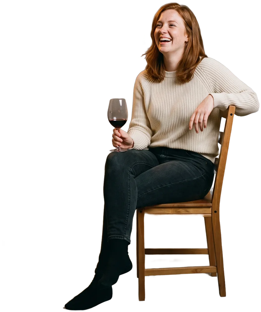 A guest laughing at a candle-lit dinner table, glass of wine in hand